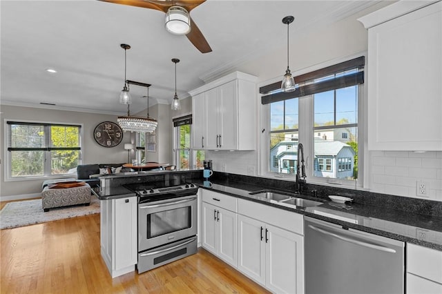 kitchen featuring crown molding, a sink, open floor plan, stainless steel appliances, and a peninsula