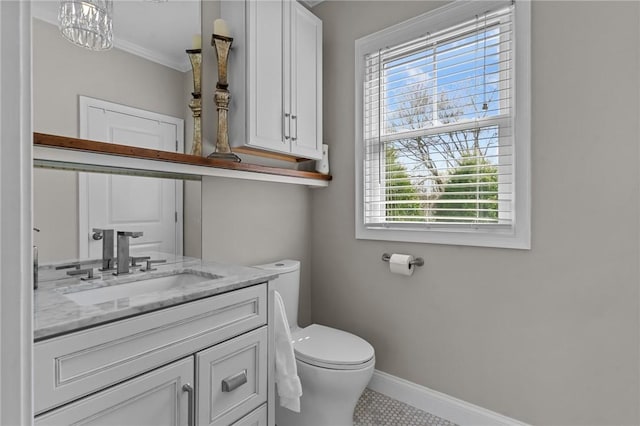 bathroom featuring vanity, toilet, baseboards, and ornamental molding