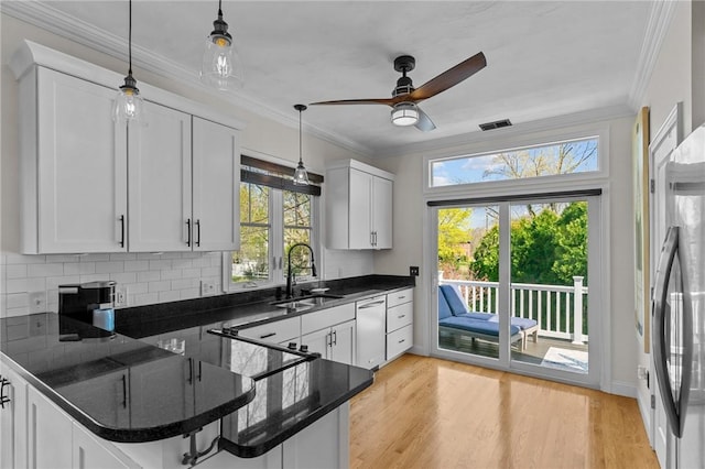 kitchen with white cabinets, plenty of natural light, backsplash, a sink, and hanging light fixtures