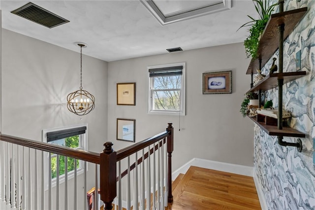 stairway with baseboards, a notable chandelier, wood finished floors, and visible vents