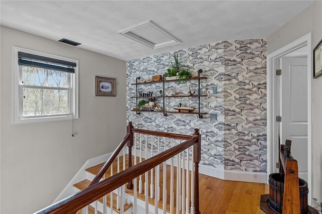 stairway with visible vents, wallpapered walls, baseboards, attic access, and wood finished floors