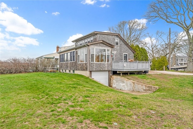back of property featuring a wooden deck, driveway, a yard, and a garage