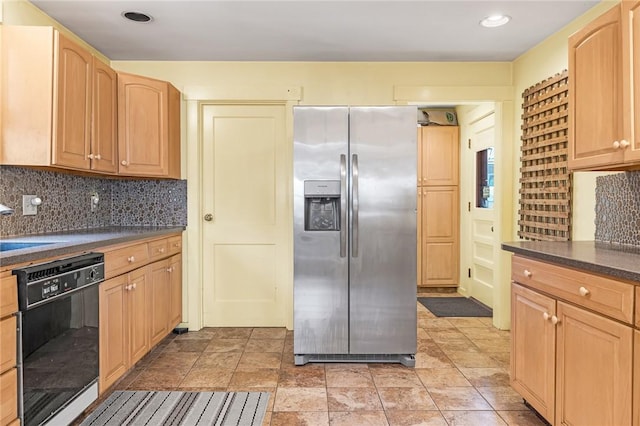 kitchen featuring dark countertops, decorative backsplash, light brown cabinetry, stainless steel fridge, and dishwasher