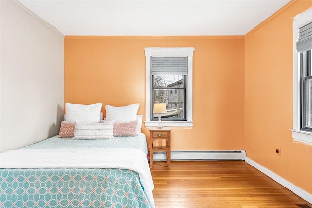 bedroom featuring wood-type flooring, baseboards, crown molding, and a baseboard heating unit