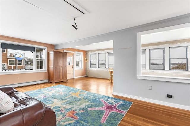 living area featuring a baseboard heating unit, baseboards, and light wood finished floors