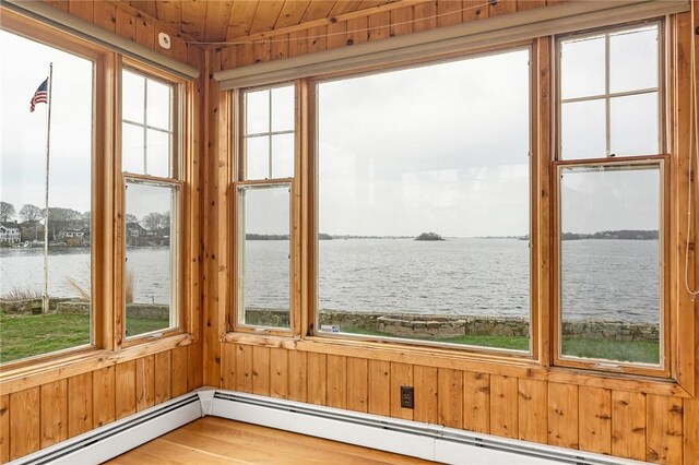 unfurnished sunroom featuring a baseboard radiator, a water view, and a healthy amount of sunlight