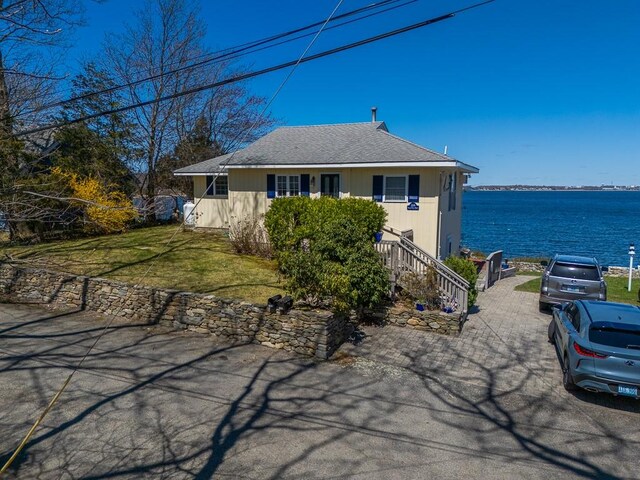 view of front of home with stairway, a front yard, and a water view