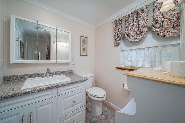 bathroom with toilet, baseboards, vanity, and crown molding