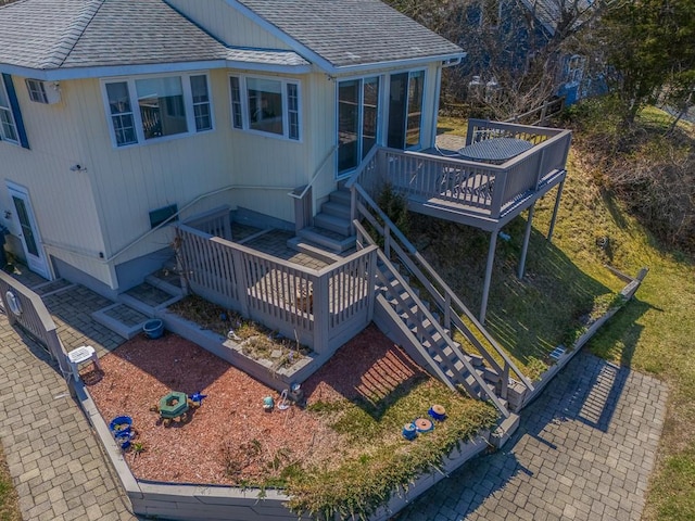 rear view of house with roof with shingles, stairway, and a deck