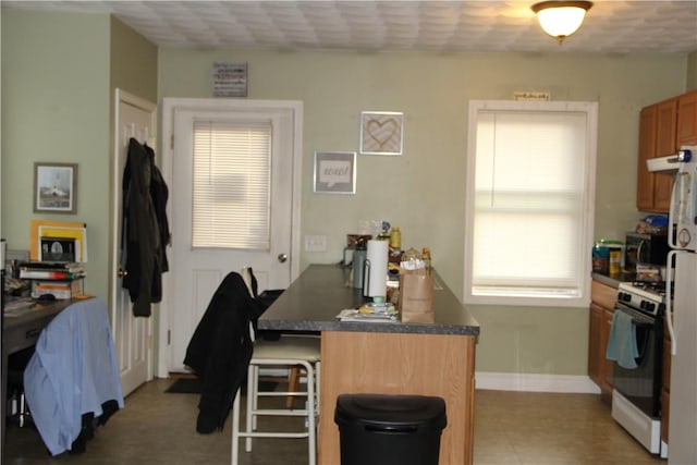 372 Mishnock Rd, West Greenwich, RI 02817 - kitchen featuring white gas range, a peninsula, a breakfast bar, dark countertops, and under cabinet range hood