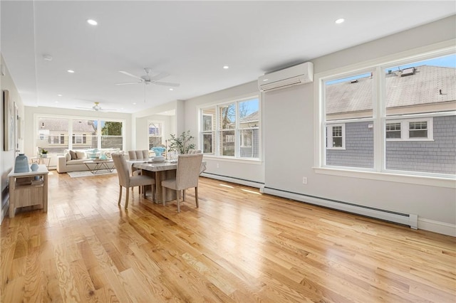 dining room with a wall mounted air conditioner, light wood-style flooring, a baseboard heating unit, and a wealth of natural light