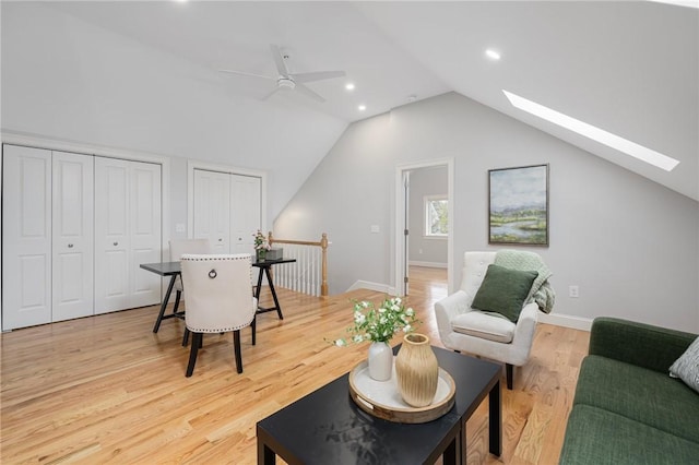 interior space featuring vaulted ceiling with skylight, ceiling fan, baseboards, recessed lighting, and light wood-style flooring