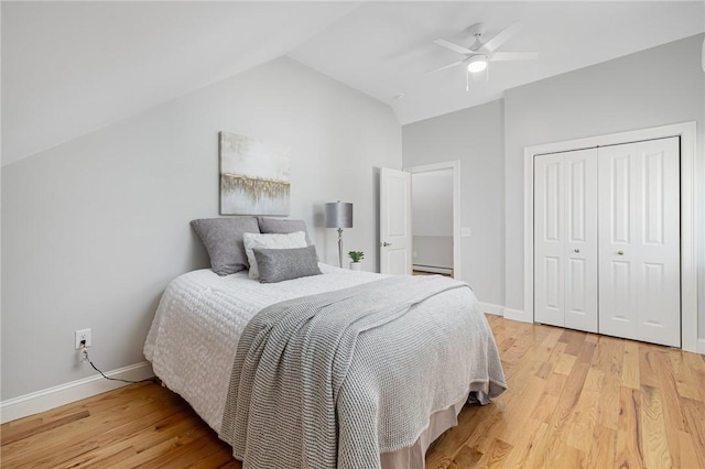 bedroom with light wood-style floors, vaulted ceiling, baseboards, and a closet