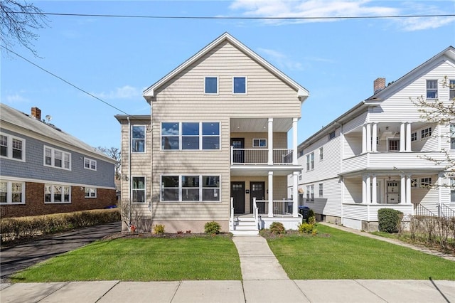 townhome / multi-family property featuring a balcony, covered porch, and a front yard