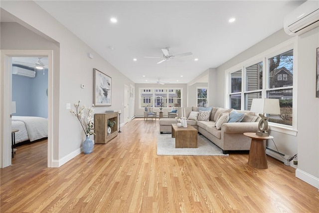 living room with an AC wall unit, a ceiling fan, light wood finished floors, and baseboards