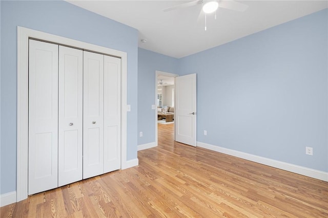 unfurnished bedroom with baseboards, ceiling fan, a closet, and light wood-type flooring