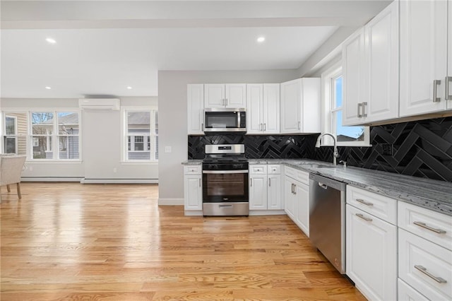 kitchen featuring white cabinetry, appliances with stainless steel finishes, a sink, and a wall mounted air conditioner