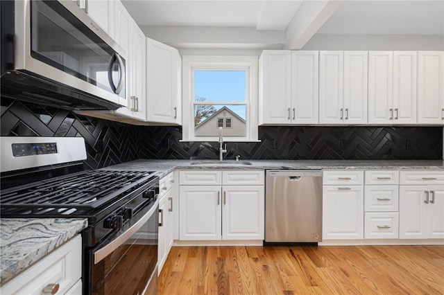 kitchen featuring white cabinetry, appliances with stainless steel finishes, a sink, and tasteful backsplash