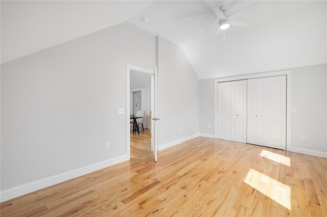 unfurnished bedroom featuring a closet, baseboards, light wood-type flooring, a ceiling fan, and vaulted ceiling