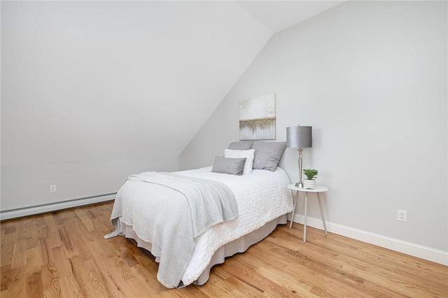 bedroom with wood finished floors, baseboards, a baseboard heating unit, and vaulted ceiling