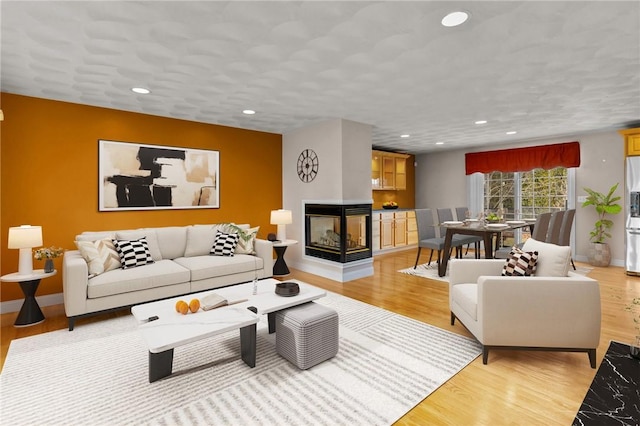 living room featuring recessed lighting, light wood-style floors, and a multi sided fireplace