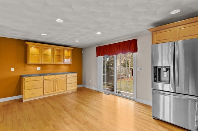 kitchen featuring glass insert cabinets, baseboards, stainless steel fridge, and light wood-style floors