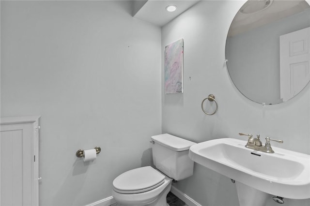 half bathroom featuring baseboards, a sink, and toilet