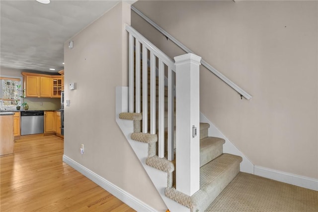 staircase with wood finished floors, baseboards, and recessed lighting