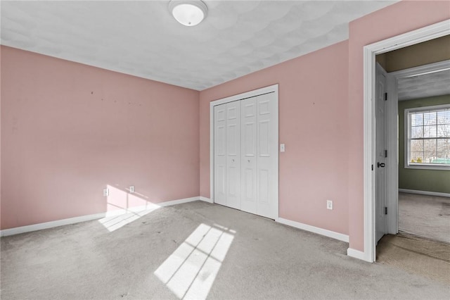 unfurnished bedroom with carpet, a closet, and baseboards