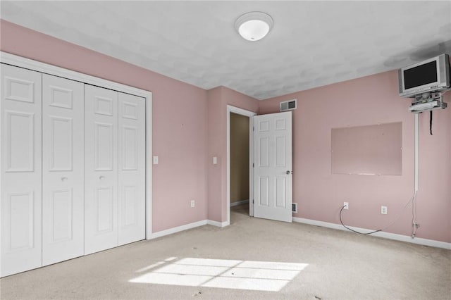 unfurnished bedroom featuring a closet, visible vents, baseboards, and light colored carpet