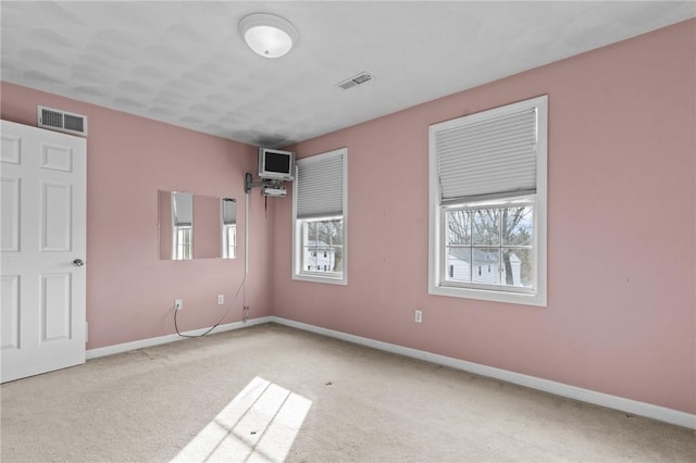 carpeted spare room featuring visible vents and baseboards
