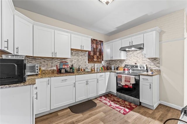 kitchen featuring stainless steel electric range oven, light wood-type flooring, white cabinetry, black microwave, and under cabinet range hood