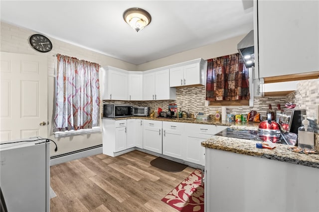 kitchen with a baseboard heating unit, light wood-style flooring, stainless steel microwave, white cabinetry, and light stone countertops