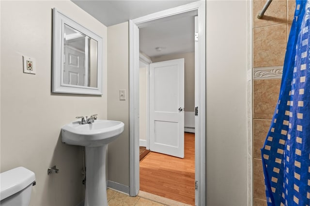full bathroom featuring a sink, toilet, baseboard heating, tile patterned flooring, and a shower with shower curtain