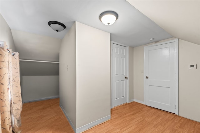 additional living space with light wood-style floors, lofted ceiling, and baseboards