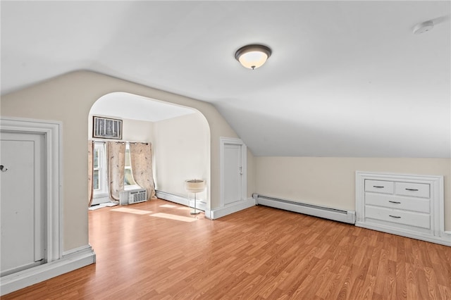 bonus room featuring a baseboard heating unit, lofted ceiling, and light wood-type flooring