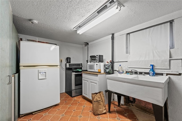 kitchen featuring a textured ceiling, light tile patterned floors, and white appliances