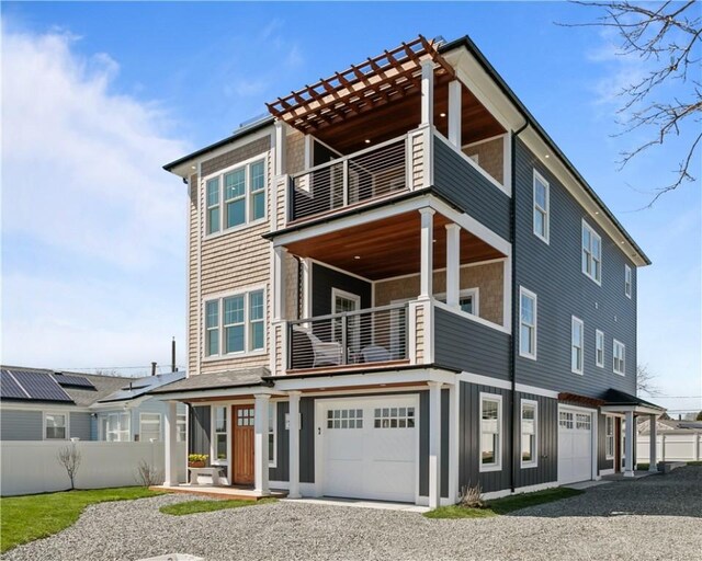 view of front of house featuring a balcony, board and batten siding, fence, a garage, and gravel driveway