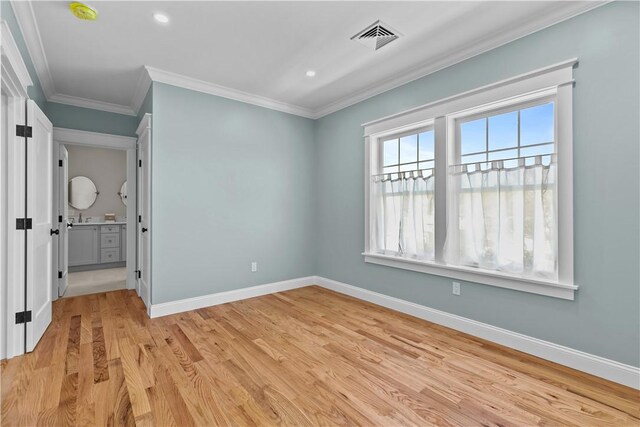 unfurnished bedroom featuring baseboards, crown molding, visible vents, and light wood-style flooring