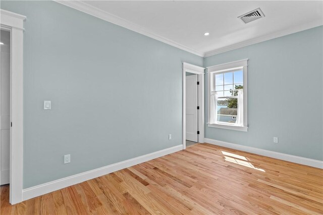 unfurnished room featuring wood finished floors, visible vents, baseboards, and ornamental molding