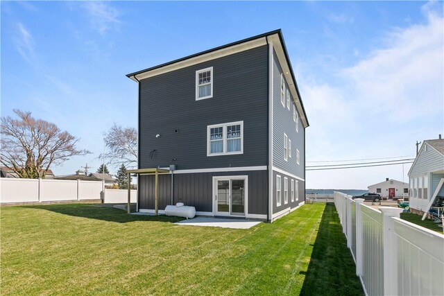back of property with board and batten siding, a lawn, a fenced backyard, and a patio