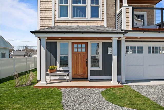 entrance to property with fence, covered porch, board and batten siding, and a garage