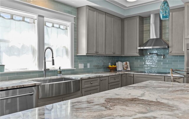 kitchen with stainless steel dishwasher, a sink, wall chimney exhaust hood, black electric stovetop, and gray cabinetry