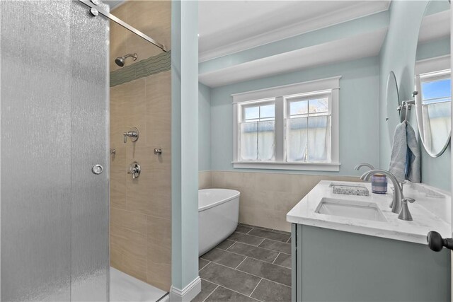 full bath with tile walls, a wealth of natural light, a stall shower, and a sink