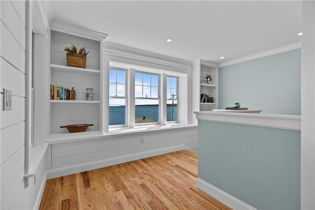 interior space with recessed lighting, wood finished floors, a water view, and ornamental molding