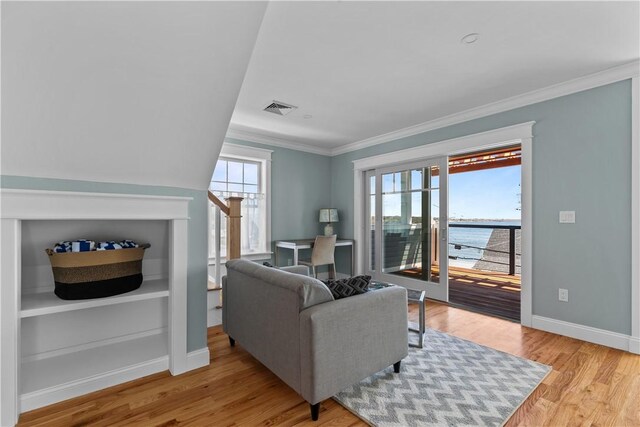 living area with baseboards, crown molding, wood finished floors, and visible vents