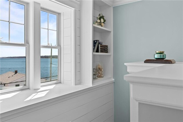 interior space with built in shelves, ornamental molding, and a water view