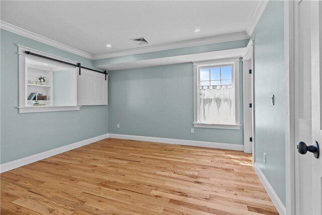 unfurnished bedroom featuring baseboards, ornamental molding, visible vents, and light wood-style flooring
