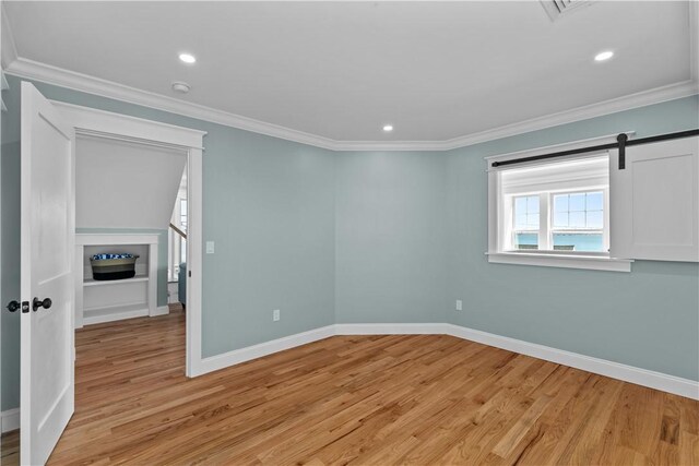 empty room featuring light wood-type flooring, baseboards, and ornamental molding