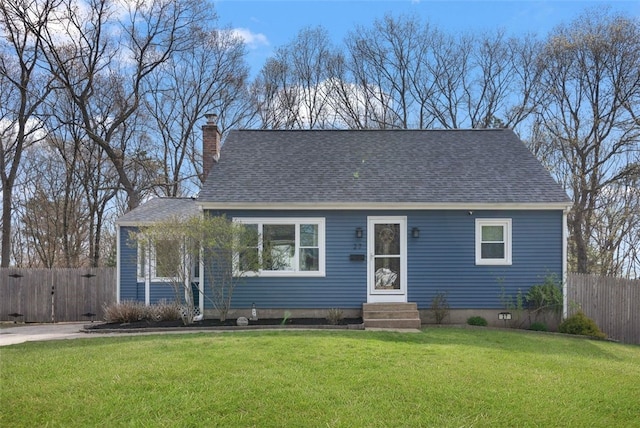 cape cod home featuring a chimney, fence, entry steps, roof with shingles, and a front lawn